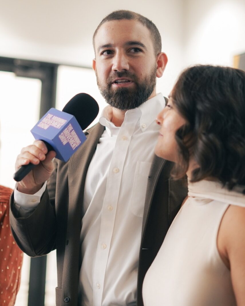 Parker Fritts holding a Morning Movement Show microphone while interviewing a guest.